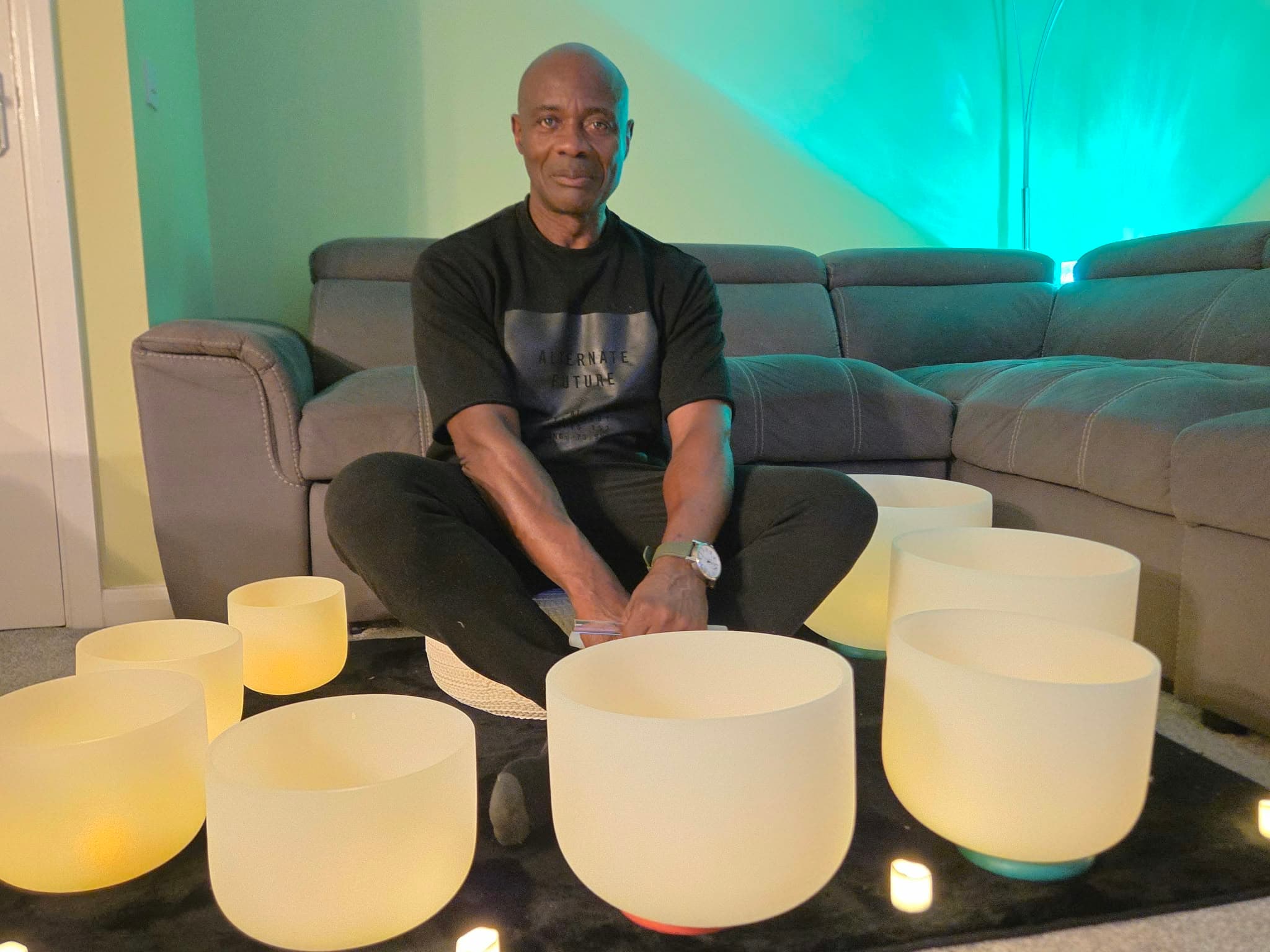 Clinton Oliver sitting cross-legged behind a set of glowing crystal singing bowls